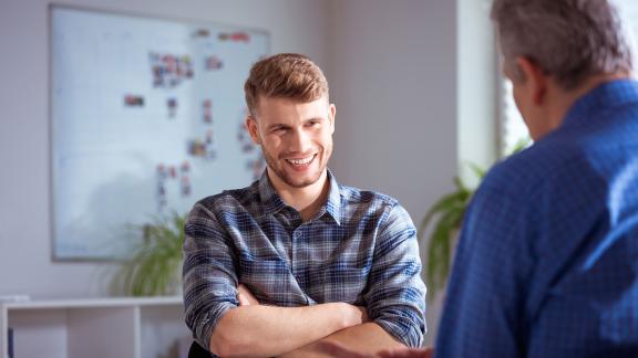 Two men talking, one is smiling.